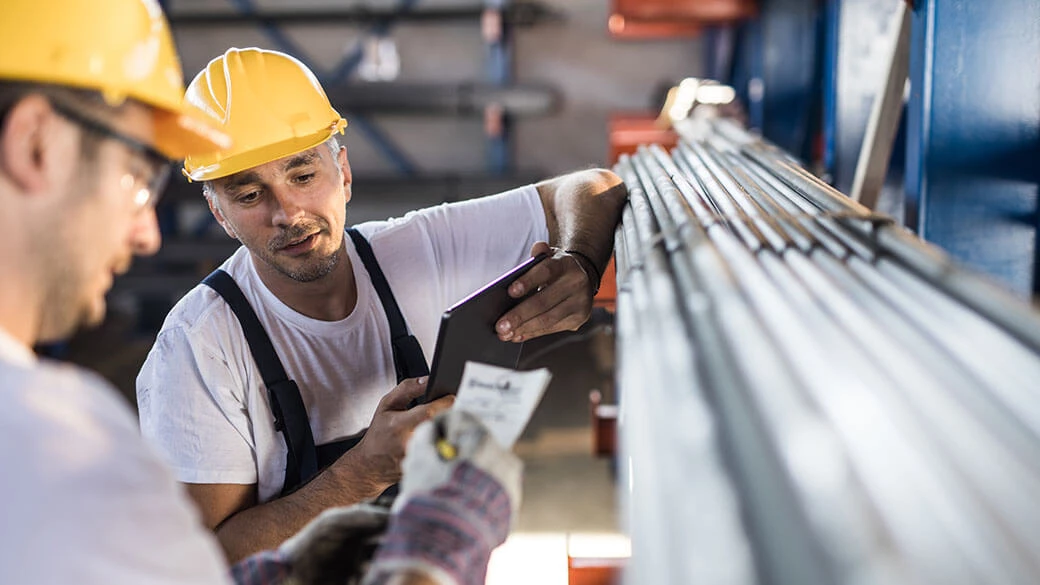 workers looking at tablet and working with steel